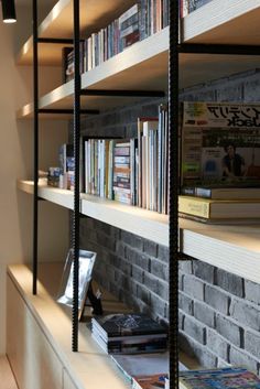 a bookshelf filled with lots of books next to a brick wall