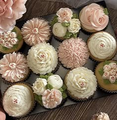 there are many cupcakes in the box on the table and one is decorated with flowers