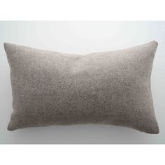 a grey and white pillow on a white wall with a light brown border in the background