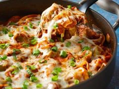 a skillet filled with lasagna covered in cheese and green onion garnish