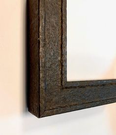 a wooden frame hanging on the wall with a mirror in it's center,