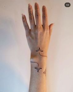 a woman's hand with a small tattoo on her left wrist and the other arm