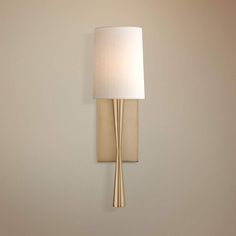 a wall light with a white shade on the side and a beige lamp behind it