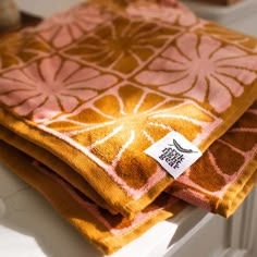 two towels sitting on top of a white counter next to a window sill with a tag hanging from it