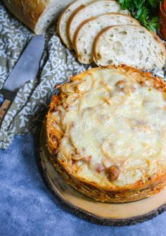 a cheese pizza on a wooden platter with slices of bread