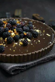 a chocolate tart topped with blackberries and other toppings on top of it