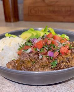 a bowl filled with meat and vegetables on top of a table next to some rice