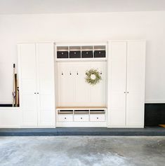 an empty room with white cabinets and a wreath on the wall