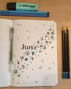 an open notebook with the word june written in cursive writing on it next to two pencils