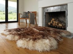 a living room with a fire place, chair and rug on the wooden flooring