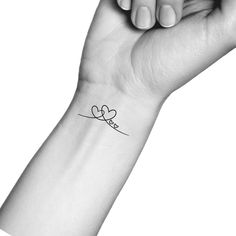 a woman's wrist tattoo with the word love written in cursive font