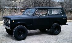 an old black truck is parked in the dirt