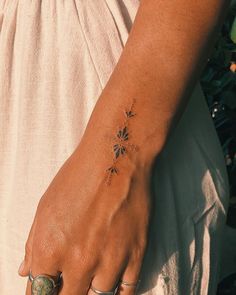 a woman's hand with a flower tattoo on her left wrist and two rings