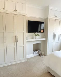 a bedroom with white closets and a flat screen tv on the wall above it