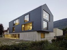 the house is made out of concrete and has large windows