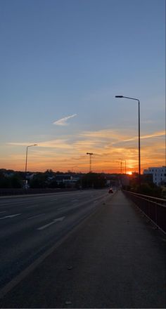 the sun is setting over an empty street with no cars or people on it,