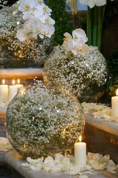 three vases filled with flowers and lit candles sitting on steps next to each other