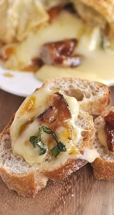 two pieces of bread with cheese and bacon on them sitting on a wooden table next to another piece of bread