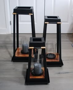 three black candle holders with candles in them sitting on the floor next to a door