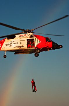 a man is suspended from a helicopter by a rainbow