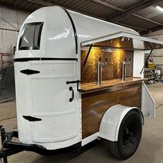 an old fashioned food truck is parked in a garage with its door open and wood paneling on the side