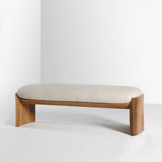 a wooden bench sitting on top of a white floor in front of a white wall