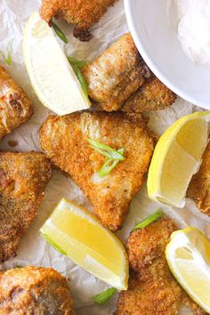 fried fish with lemon wedges and sour cream on the side, ready to be eaten