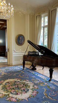 a grand piano sitting in the middle of a room with chandelier above it