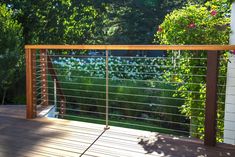 a wooden deck with metal railings and trees in the backgroung area