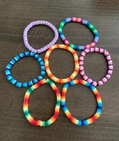 six colorful bracelets sitting on top of a wooden table