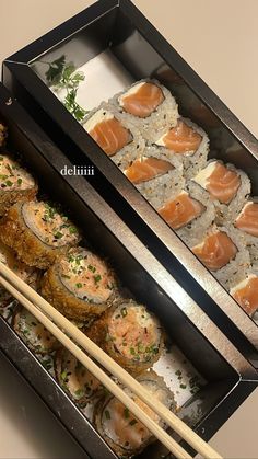 two trays filled with sushi and chopsticks