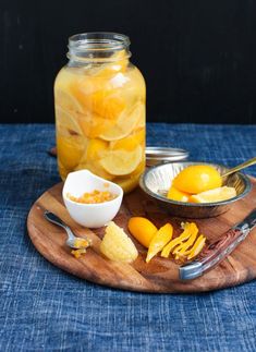 a wooden plate topped with sliced lemons and orange slices next to a mason jar