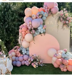 an outdoor event with balloons and flowers on the wall, in front of a sign that says joy