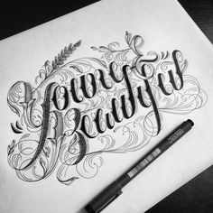 the lettering is drawn on paper with a pen and some ink in front of it