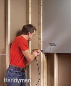 a man in red shirt working on a wall mounted air conditioner with power cord