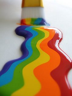 an image of a rainbow colored stream of liquid flowing down the side of a white surface