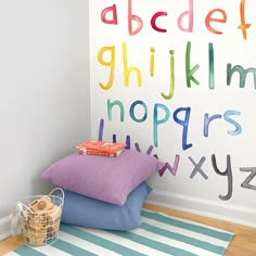 a child's room with colorful letters on the wall and pillows in front of it