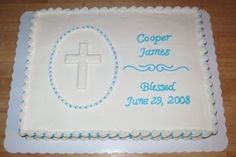 a white cake with blue lettering and a cross on the top is sitting on a wooden table