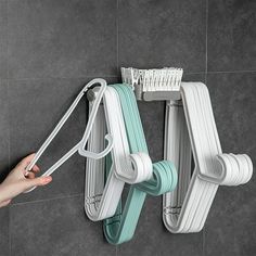 a person is holding two toothbrushes in front of a wall mounted rack with hooks on it