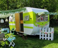 a green and white trailer parked on top of a grass covered field next to a picnic table