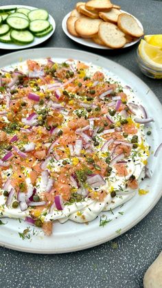 a pizza sitting on top of a white plate next to sliced up cucumbers