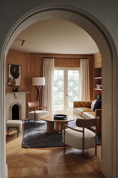 a living room filled with furniture and a fire place next to a doorway that leads to a sitting area