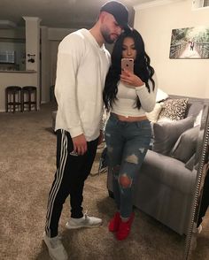 a man standing next to a woman in a living room while holding a cell phone