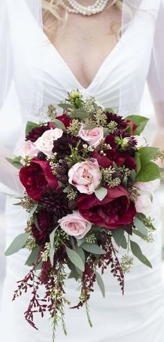 a bride holding a bouquet of red and pink flowers