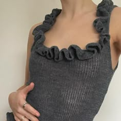 a woman wearing a gray top with ruffles on it