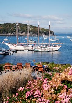 a group of people sitting at tables in front of a large boat on the water