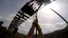 someone is hanging from the top of a ladder with safety equipment on their hands while another person stands below them