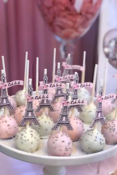 cake pops with pink and white frosting in front of the eiffel tower