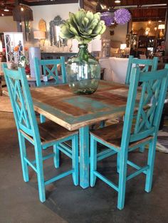 a wooden table with blue chairs and a vase filled with flowers on top of it