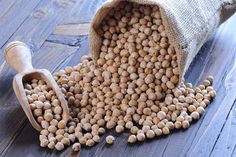 a bag full of chickpeas sitting on top of a wooden floor next to a scoop